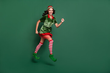 Full length body size view of attractive cheery girl Santa helper jumping running isolated over...