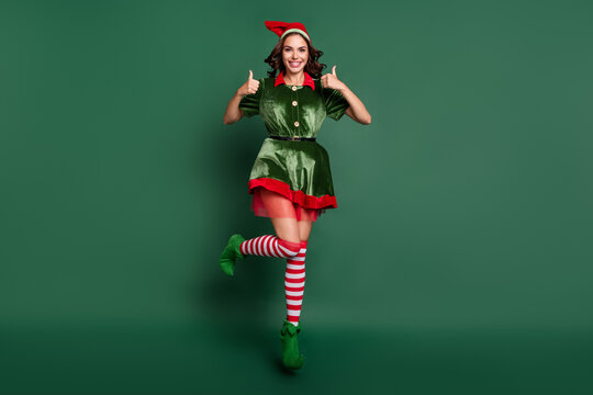 Full size photo of young girl happy positive smile jump up show thumb-up like fine choose isolated over green color background