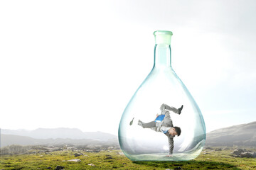 Young businessman dancing inside glass bottle