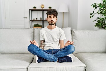 Young hispanic man concentrate meditating at home