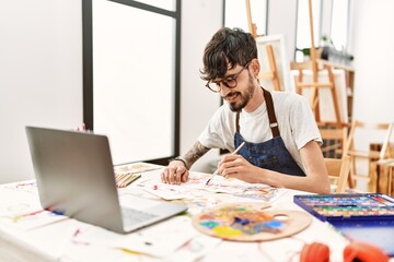Young hispanic artist man having online paint class at art studio.