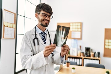 Young hispanic doctor man holding xray working at clinic