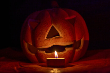 A carved pumpkin and a candle in a dark background - halloween concept