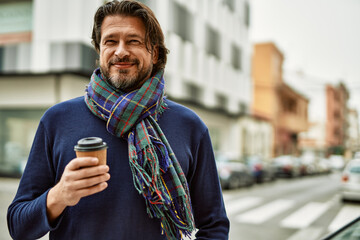 Middle age handsome man drinking a take away cup of coffee at the town