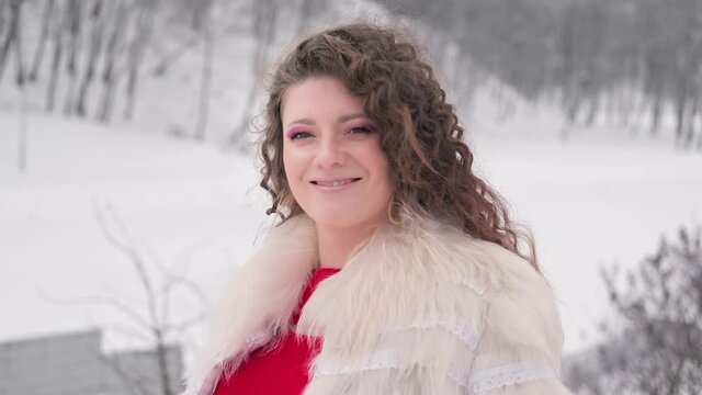 Portrait of young woman in winter park. Cute female looking at camera. Close-up of woman enjoys nature. 4K, UHD