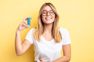 pretty blonde girl laughing out loud at some hilarious joke. asthma inhaler concept