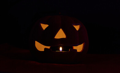 A glowing carved pumpkin in a black background - halloween concept
