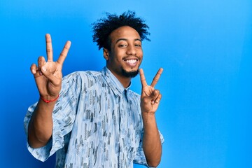 Young african american man with beard wearing casual clothes smiling looking to the camera showing...