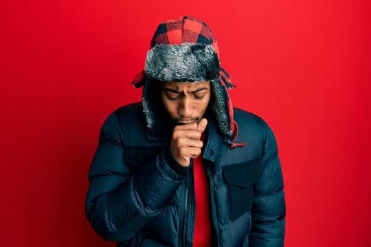 Young african american man with beard wearing winter hat and coat feeling unwell and coughing as symptom for cold or bronchitis. health care concept.