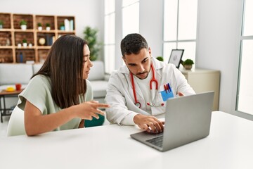 Obraz premium Doctor explain treatment to latin woman using laptop at clinic.