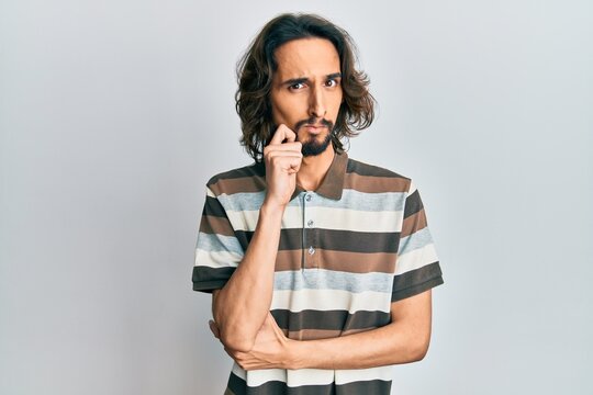 Young hispanic man wearing casual clothes thinking concentrated about doubt with finger on chin and looking up wondering