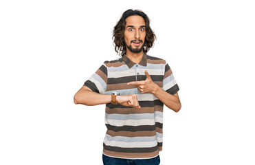 Young hispanic man wearing casual clothes in hurry pointing to watch time, impatience, upset and...
