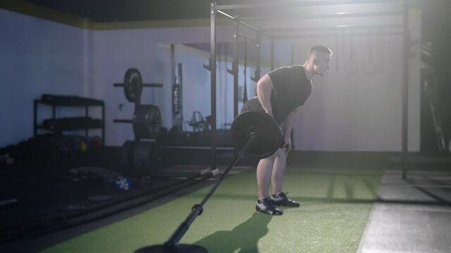 Fitness man exercise landmine row with barbell weightlifting under spotlight 4K