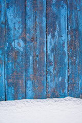 blue wood texture background with untouched snow, peeling paint on wood in winter