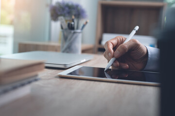 Business man using stylus pen signing on digital tablet, working at office