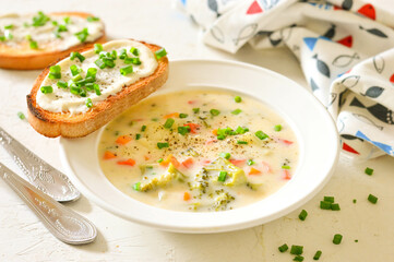 Cheese (creamy) soup with broccoli, carrots, herbs, croutons. White dishes and white background....