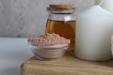 spa treatments rest relax. Oil clay for wrapping candle mask white towel massage on a wooden tray on a white gray concrete background close-up view from the side. Home body care