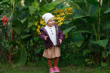 the baby dances near the yellow autumn flowers