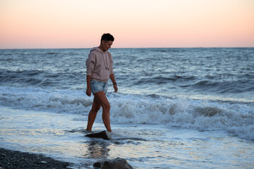 Sad woman walks along the beach with dramatic cold waves