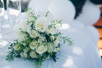 White rose bouquet on table with spots of sunlight during a garden wedding. Copy space.