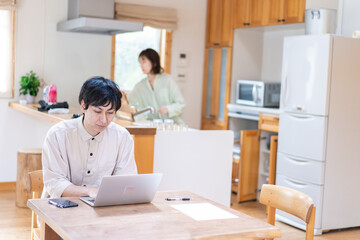 テレワークをする夫婦と子供