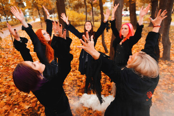 Fototapeta na wymiar Coven of witches, a group of friends as witches on Halloween perform a ritual, lead a round dance and recite spells.