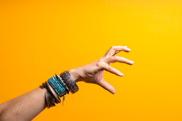 Hand gestures. To grab something. Women's hand with lots of bracelets, youth fun style.
