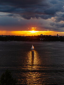 A sailboat sailing in Helsinki Finland reflected in sea water during the sunset lights