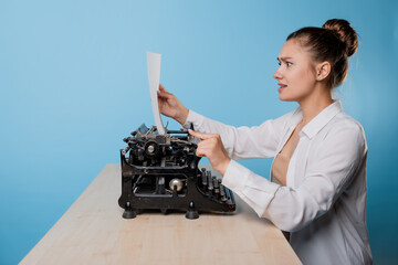 young woman writer at a typewriter is shocked by what she wrote,