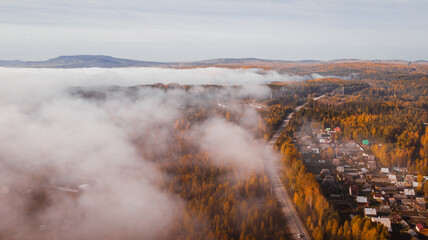 Natural background, aerial view. Autumn nature in the forest and the road passing through it.