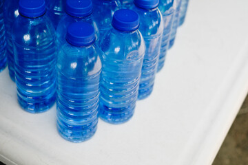 Several lined up drinking bottled water with no label on white table. Selective focus. Copy space.