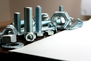 Several metal bolts and nuts on a wooden table next to a white background