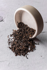 selective focus, natural black leaf tea. brewing in a clay bowl. vertical angle, macro. on a light background. for menus and cafes
