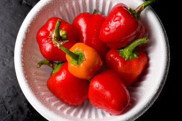 Miniature Sweet Red and Yellow Peppers in a White Bowl on Dark Stone