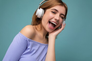 Closeup photo of attractive happy smiling young blonde woman wearing blue crop top isolated over...