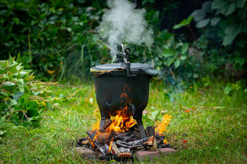 Preparing potatoes in a cast iron pot. Potato dish stewed on a fire, garden and outdoor recreation....
