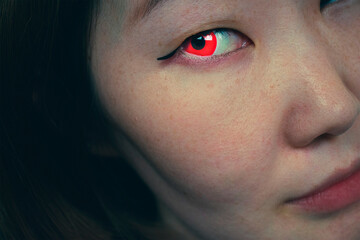 Asian girl with red eye. Woman with red contact lenses. Dark photo. Evil vampire female. Halloween concept. Face close up. Mystical woman. Spooky eyes. 