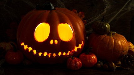 Pumpkin head Jack-o'-lantern close-up with glowing eyes and orange autumn pumpkins, very dark still life , background for Halloween