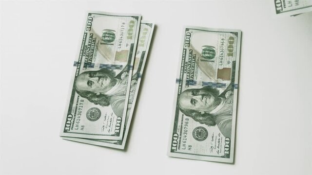 Splitting money into two unequal stacks. Men's hand puts hundred-dollar bills on the table, and then takes them away.