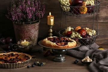 A seasonal autumn fruit pies and floral decoration on the wooden table.