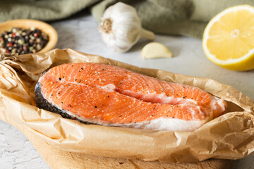 raw salmon fish steak on in baking paper, lemon, peppers