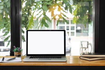 Laptop computer with white screen on table with notebook and pen and mug. Coffee shop concept.