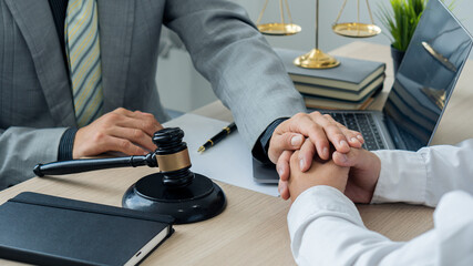 Fototapeta na wymiar Attorney-consultants hold clients' hands with trust. The center of lawyers and clients are discussing on a table with scales and hammers with laptops and notebooks. legal advisor concept