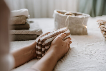 Woman folding clothes in bedroom, organizing laundry in boxes and baskets. Concept of minimalism...