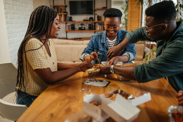 Group of young adults eating takeout food at home