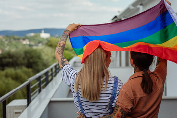 Love and pride. Two lesbians holding rainbow flag outdoors