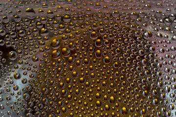 Golden drops of water are located on a silver-gold-pink background. Abstract fantasy. 3D render.