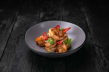 grilled seafood in a gray round plate on a dark wooden table
