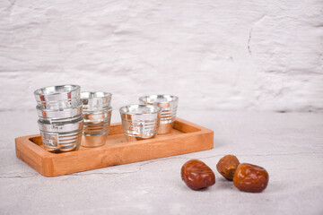 Zamzam water glass with wooden placemats and dates fruit, isolated white background and whitespace