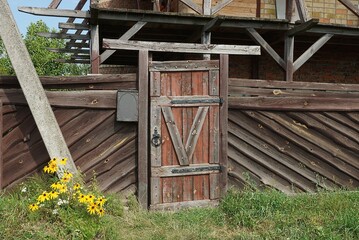 Naklejka premium one closed old wooden door and part of a brown fence wall on a rural street